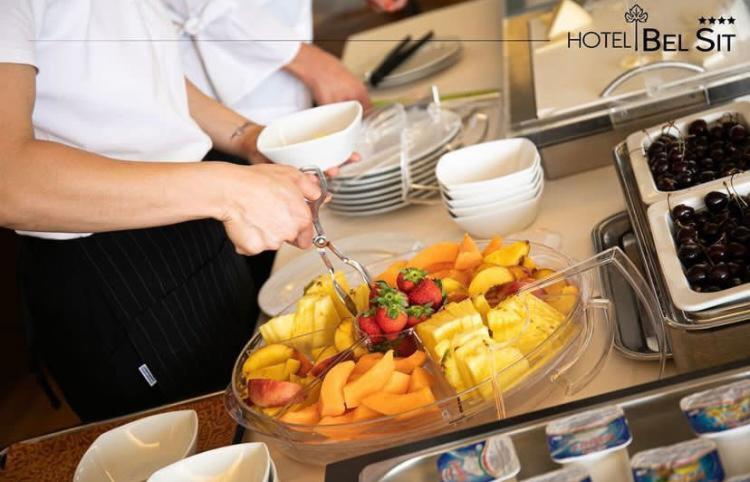 une personne coupant des fruits avec des pinces dans une cuisine dans l'établissement Hotel Bel Sit, à Meina