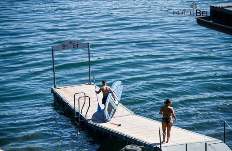 deux personnes sont debout sur un quai dans l'eau dans l'établissement Hotel Bel Sit, à Meina 97 autres photos