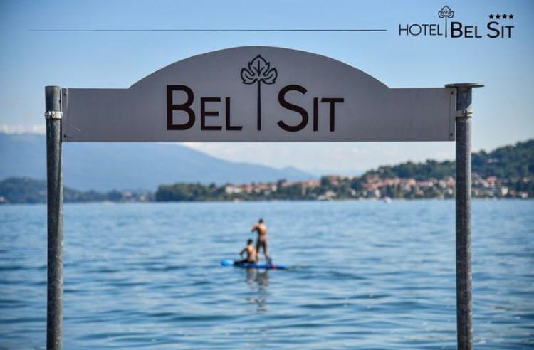 deux personnes sur une planche de surf dans l'eau sous un panneau dans l'établissement Hotel Bel Sit, à Meina