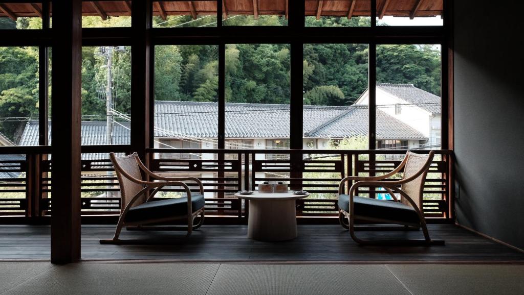 2 chaises et une table dans une chambre avec fenêtres dans l'établissement Kobayashiya -Kinosaki Onsen-, à Toyooka