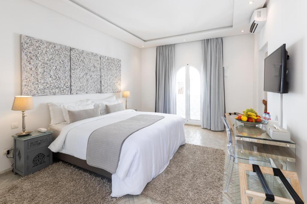 une chambre blanche avec un grand lit et un bureau dans l'établissement Riad Zyo, à Rabat