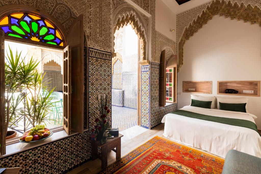 une chambre avec un lit et un vitrail dans l'établissement Riad Zyo, à Rabat