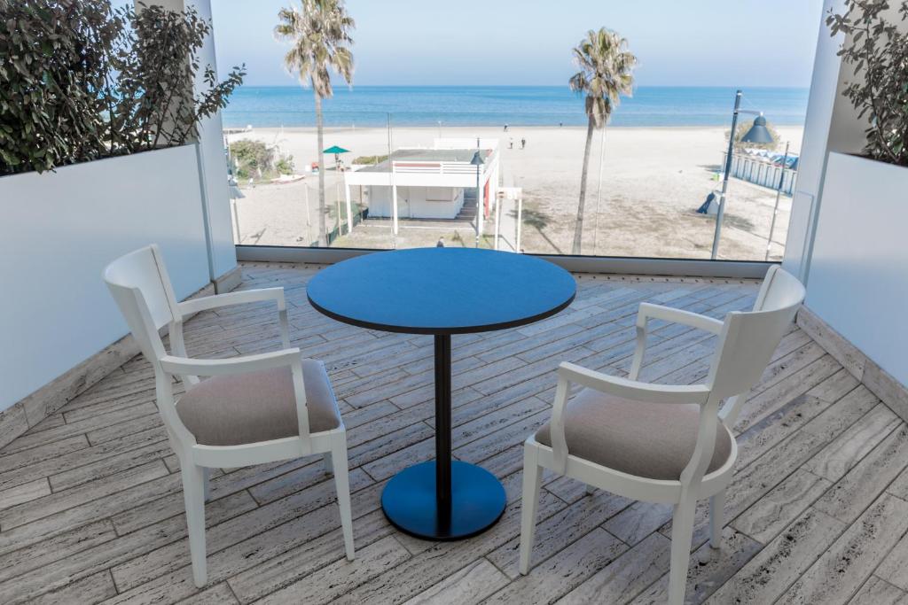 - une table et deux chaises assises sur un balcon donnant sur la plage dans l'établissement EUROPA Hotel, à Vasto