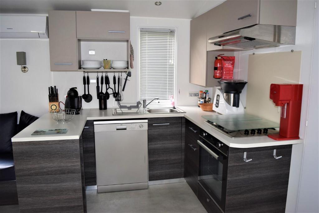 une cuisine avec un comptoir blanc et un appareil rouge dans l'établissement Spacieux Mobil-home N°502 - 2 chambres - dans Camping 4 *, à Gastes 12 autres photos