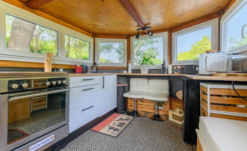 - une cuisine avec des placards blancs et des fenêtres dans une maison dans l'établissement Péniche Dondon - Gîte cocooning sur Canal du midi, à Avignonet-de-Lauragais