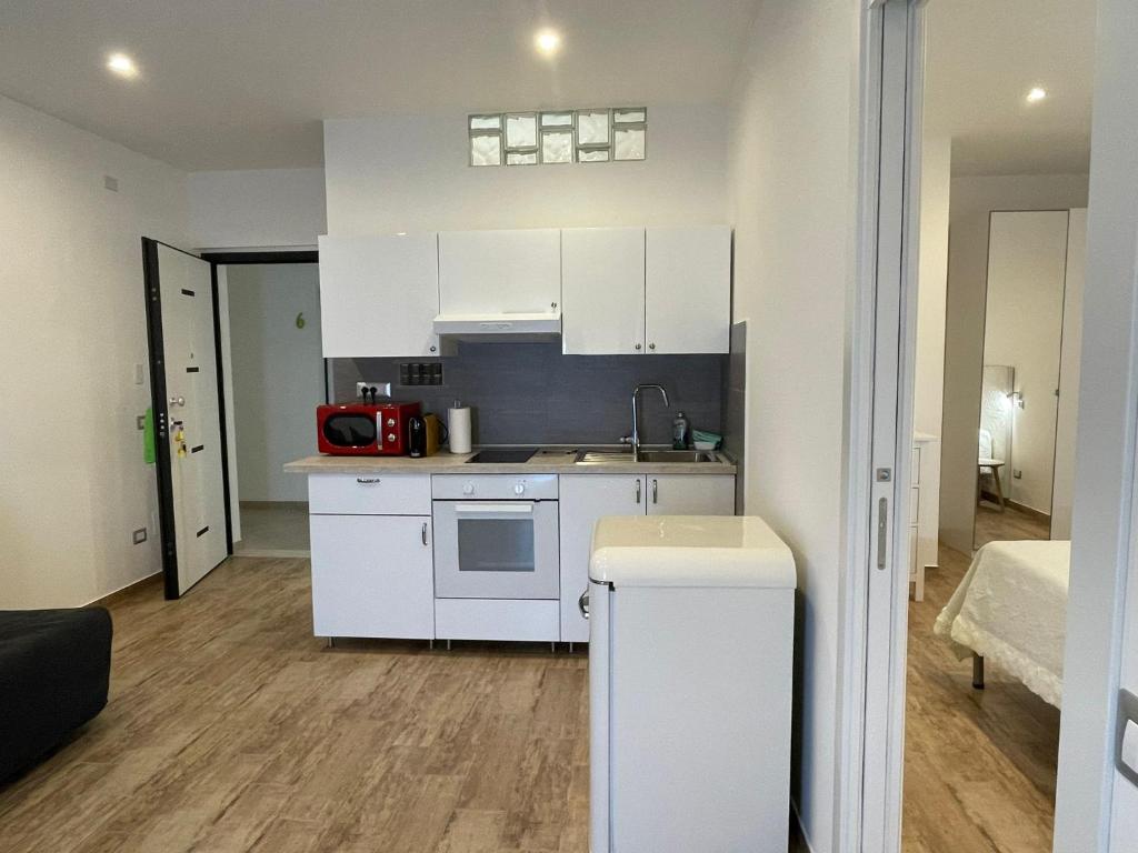 - une cuisine avec des placards blancs et un four micro-ondes rouge dans l'établissement Le Sirene Casa Vacanza, à Torvaianica