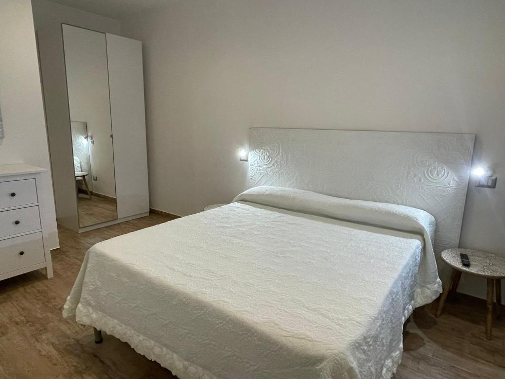une chambre avec un lit blanc et un miroir dans l'établissement Le Sirene Casa Vacanza, à Torvaianica