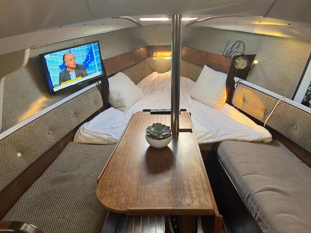 une chambre avec une table et une télévision dans un bateau dans l'établissement Voilier Loc Han, à Deauville