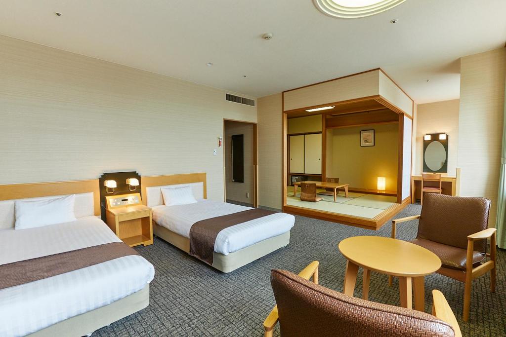 une chambre d'hôtel avec deux lits, une table et des chaises dans l'établissement KAMENOI HOTEL Ichinoseki, à Ichinoseki
