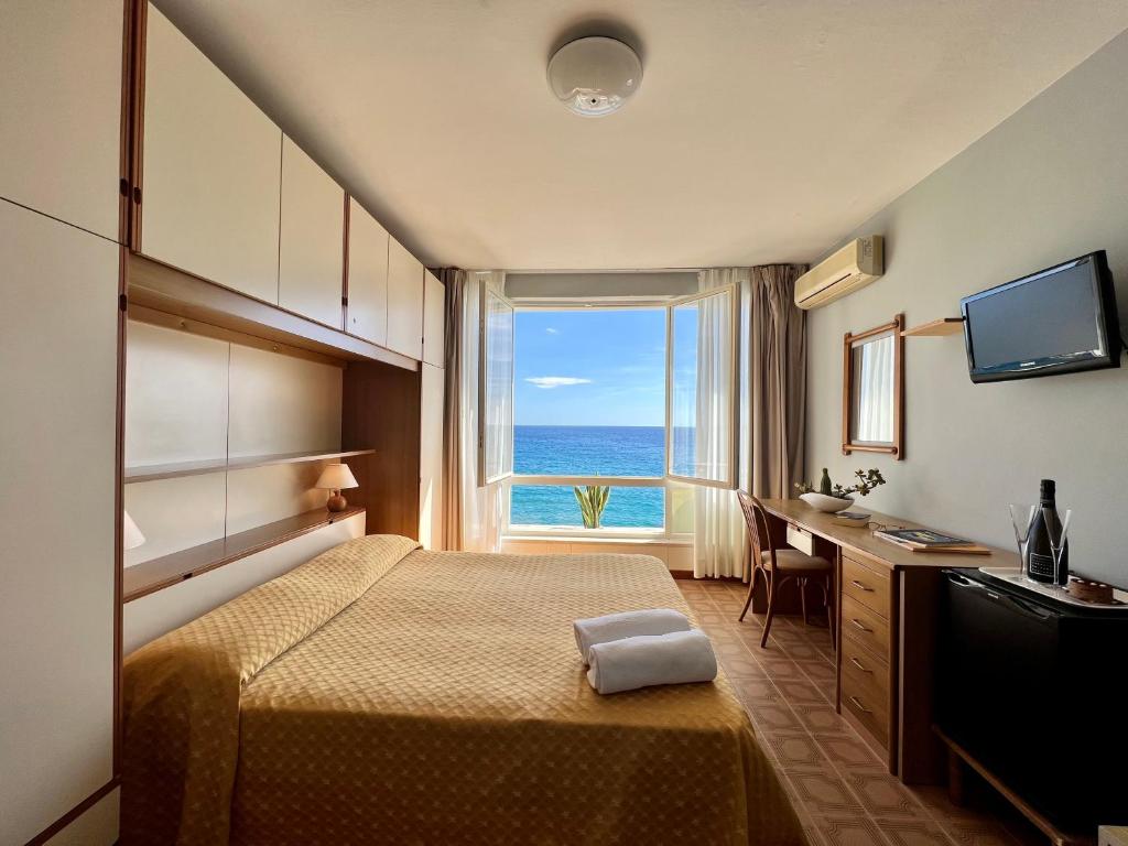 une chambre d'hôtel avec un lit, un bureau et une fenêtre dans l'établissement Hotel La Stella, à Seccheto