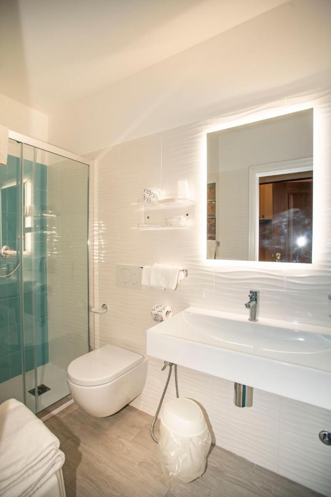 une salle de bain avec un lavabo, des toilettes et un miroir dans l'établissement Hotel La Stella, à Seccheto