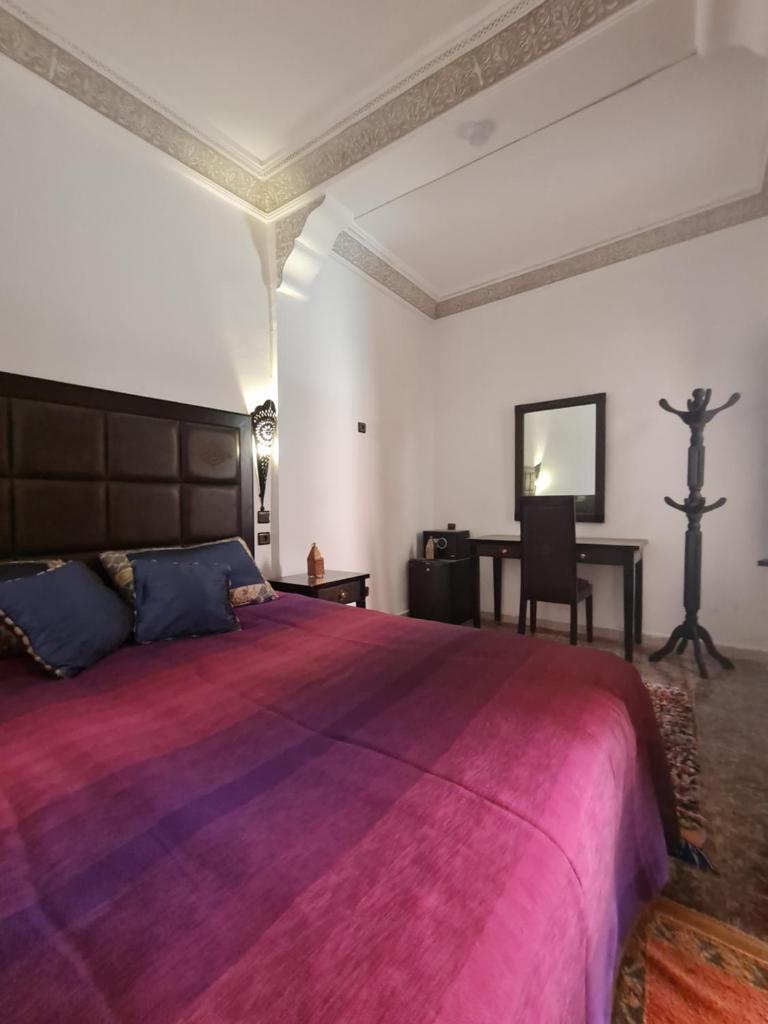 une chambre avec un grand lit et un bureau dans l'établissement Riad Kanata, à Marrakech