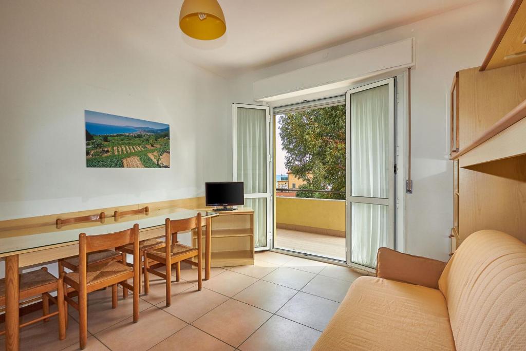 un salon avec une table, des chaises et une télévision dans l'établissement Ligure Residence Appartamenti per Vacanze, à Pietra Ligure