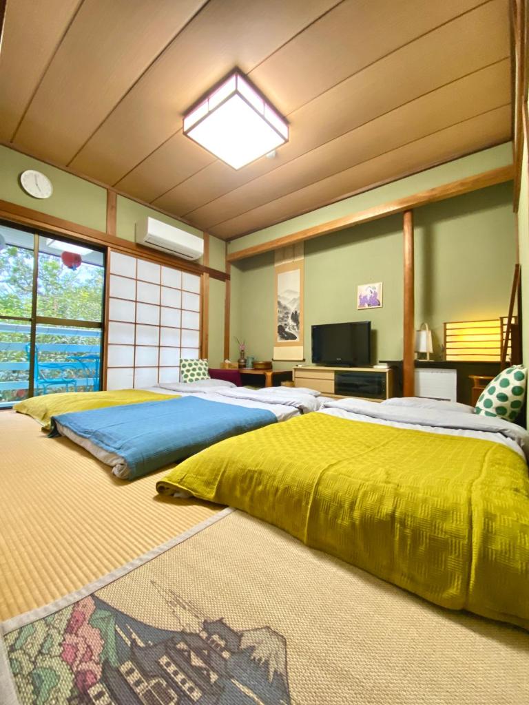 - une grande chambre avec un grand lit et des draps jaunes dans l'établissement Hanamizuki Onsen Resort, à Itō