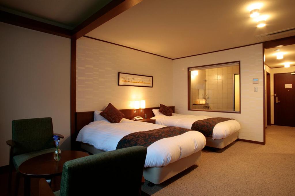 une chambre d'hôtel avec deux lits et une table dans l'établissement Shikotsuko Onsen Lake Side Villa SUIMEIKAKU-Adult Only, à Chitose