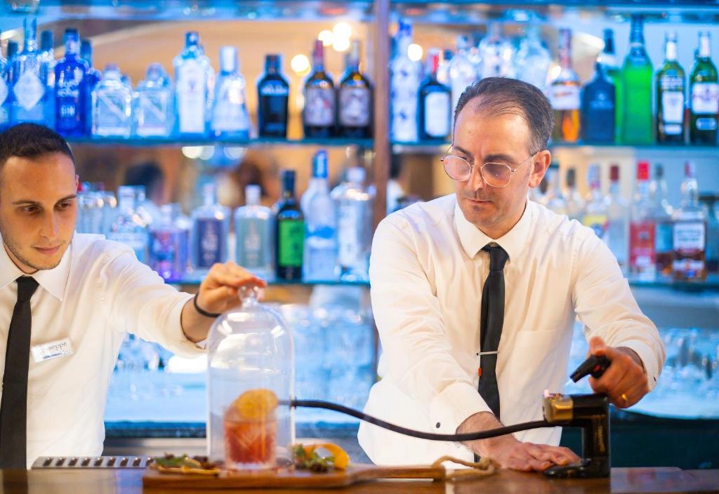 Deux hommes attachés à un bar préparant des repas dans l'établissement Hotel Kalura, à Cefalù 243 autres photos