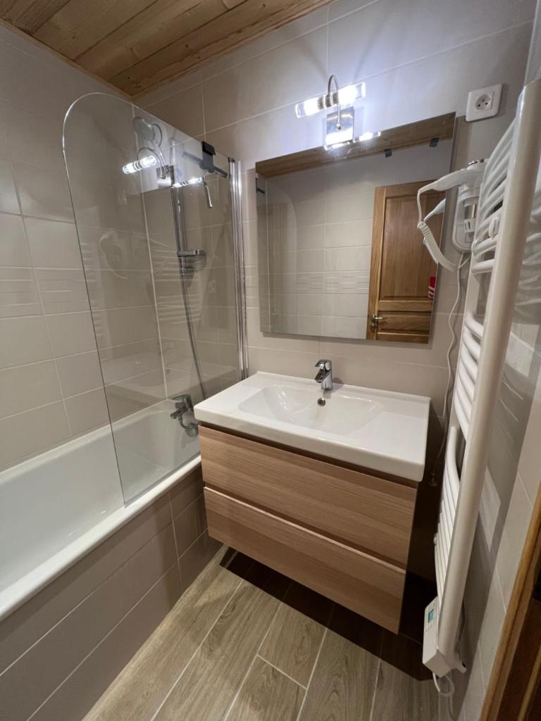 une salle de bain avec un lavabo, une douche et un miroir dans l'établissement Les Logis de Méribel, à Méribel