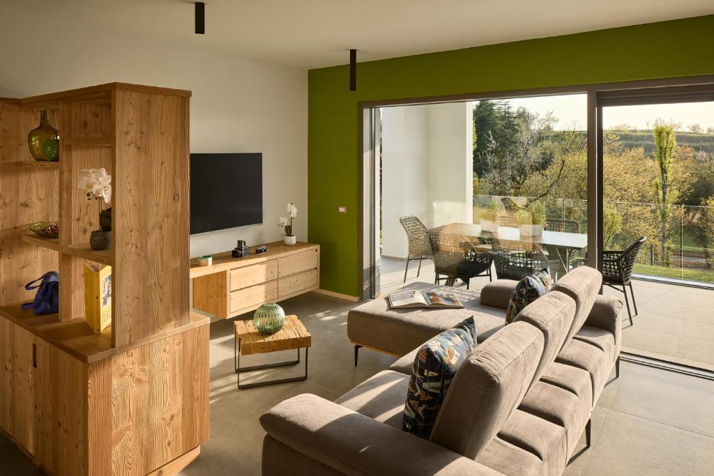 un salon avec un canapé et une télévision dans l'établissement Ca'Verde Oliva, à Costermano