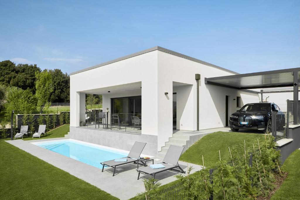 une maison blanche avec une voiture garée dans la cour dans l'établissement Ca'Verde Oliva, à Costermano