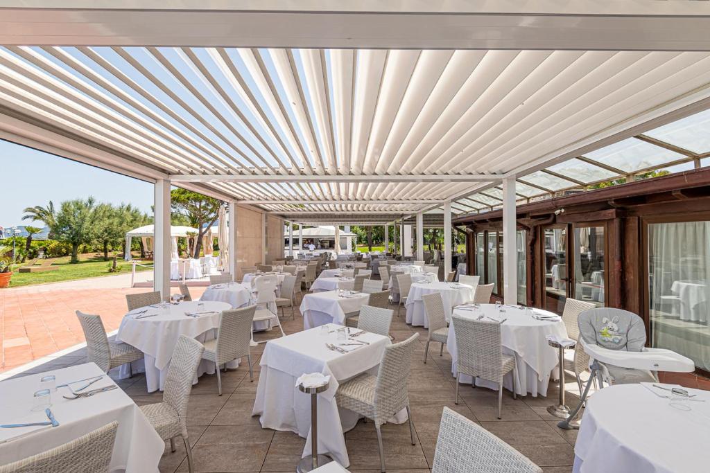 un restaurant avec des tables et des chaises blanches sur la terrasse dans l'établissement Hotel Airone isola d'Elba, à Portoferraio