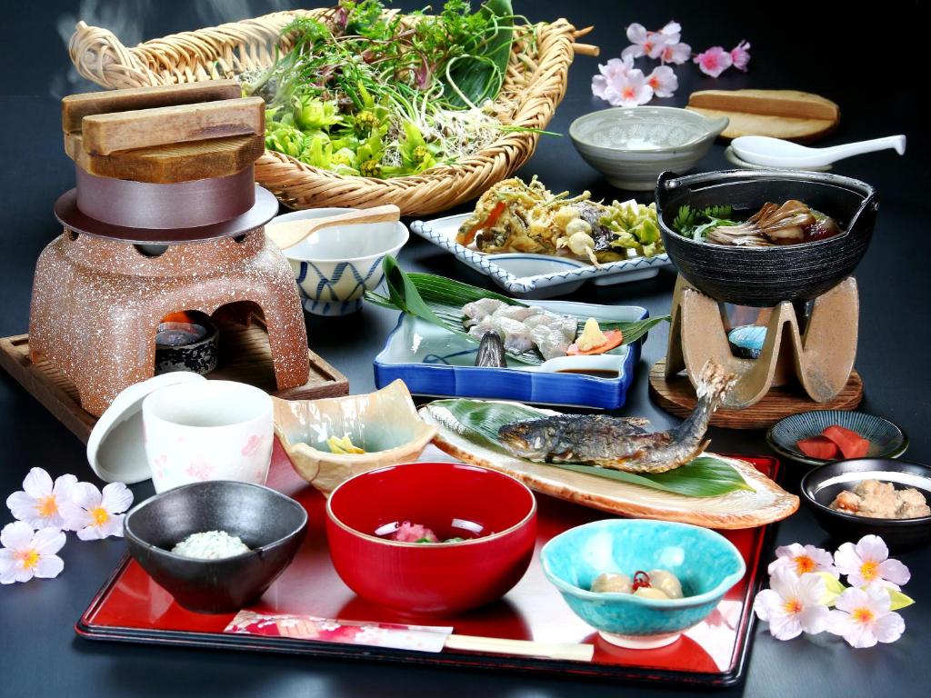 une table recouverte de bols et de assiettes de nourriture dans l'établissement 富山県 よしのや旅館, à Nanto