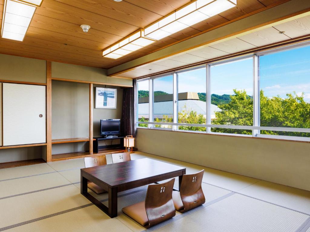 une salle à manger avec une table, des chaises et des fenêtres dans l'établissement KAMENOI HOTEL Yamato Heguri, à Heguri