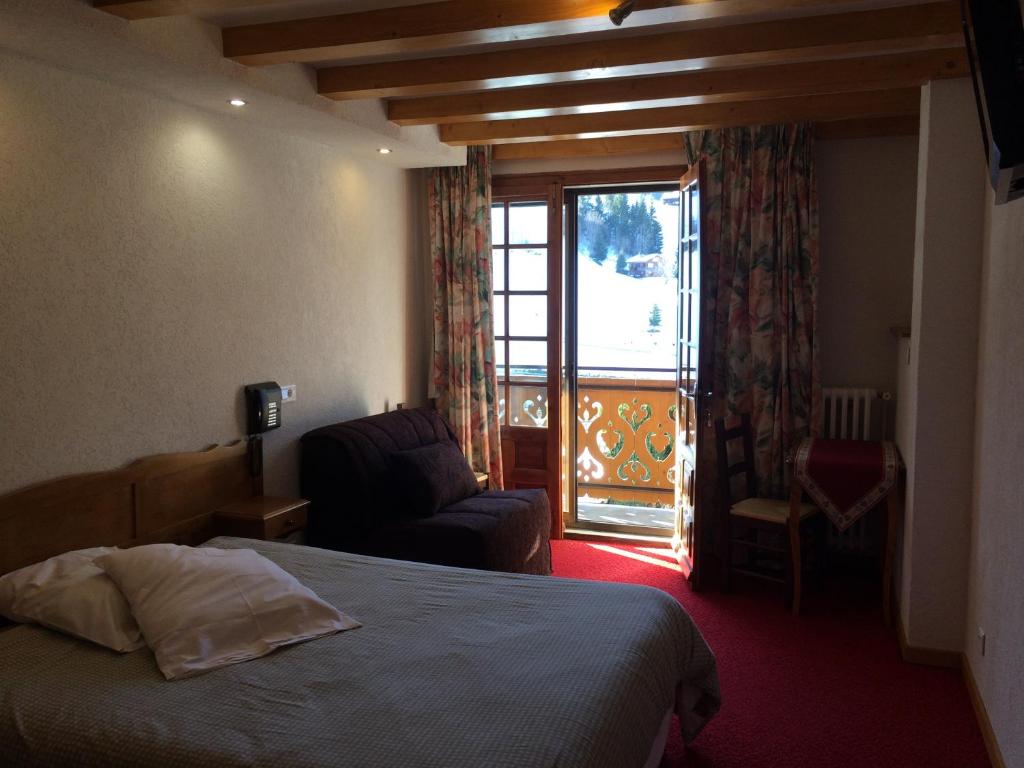 une chambre avec un lit, une chaise et une fenêtre dans l'établissement Chalet-Hôtel du Borderan, à La Clusaz
