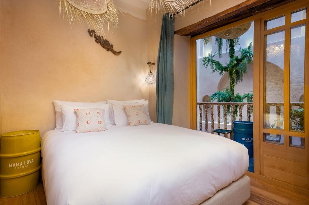 une chambre avec un lit blanc et une fenêtre dans l'établissement Mama Lova Hôtel, Riad, Restaurant & Spa, à Essaouira