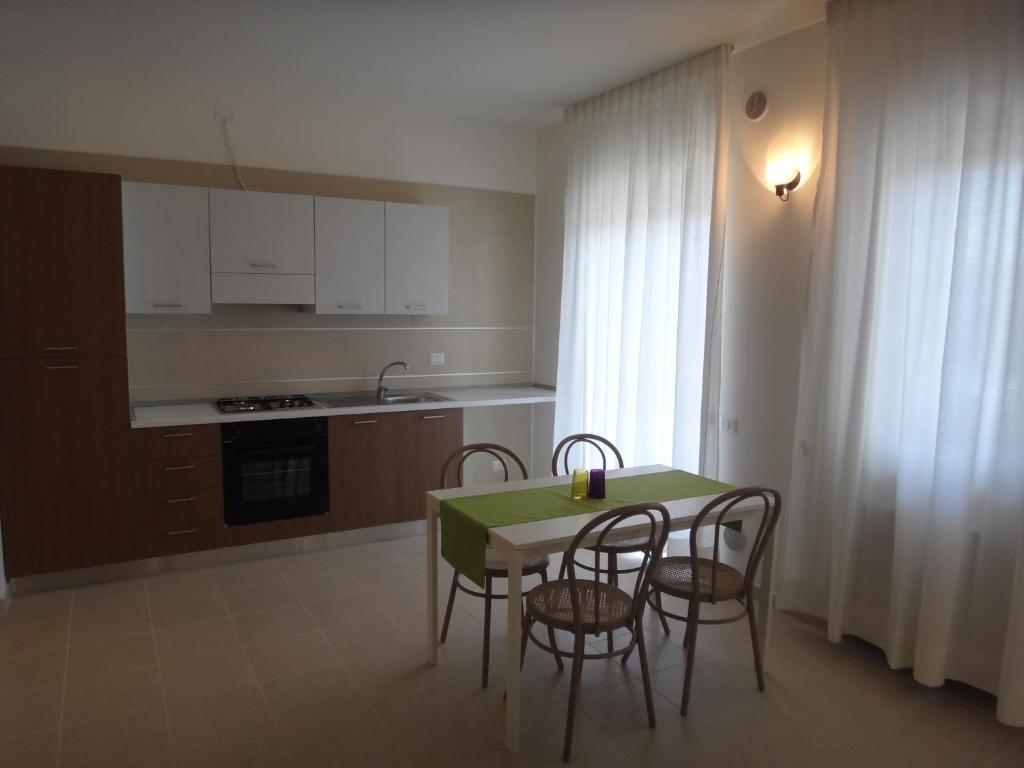 une cuisine avec une table et des chaises et une cuisine avec des armoires blanches dans l'établissement Residenza Ondanomala, à Chieuti 18 autres photos