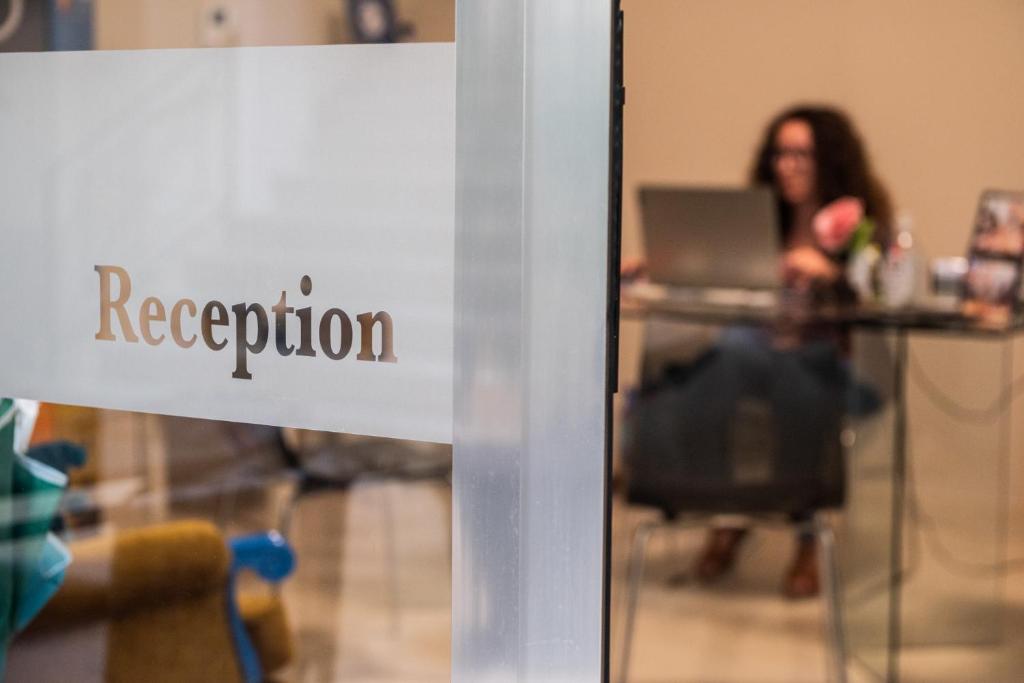 un panneau dans une pièce avec une personne assise à une table avec un ordinateur portable dans l'établissement Central Gallery Rooms- Palazzo D'Ali' Staiti XIX, à Trapani