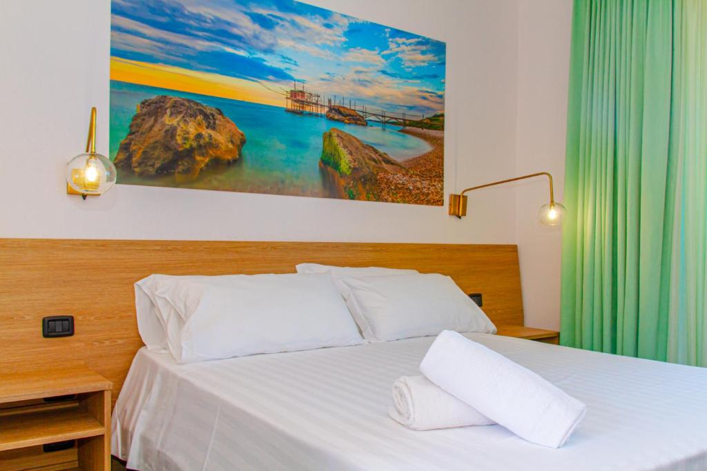 un lit avec des draps blancs et des oreillers dans une chambre dans l'établissement Residence al Palace, à Vasto