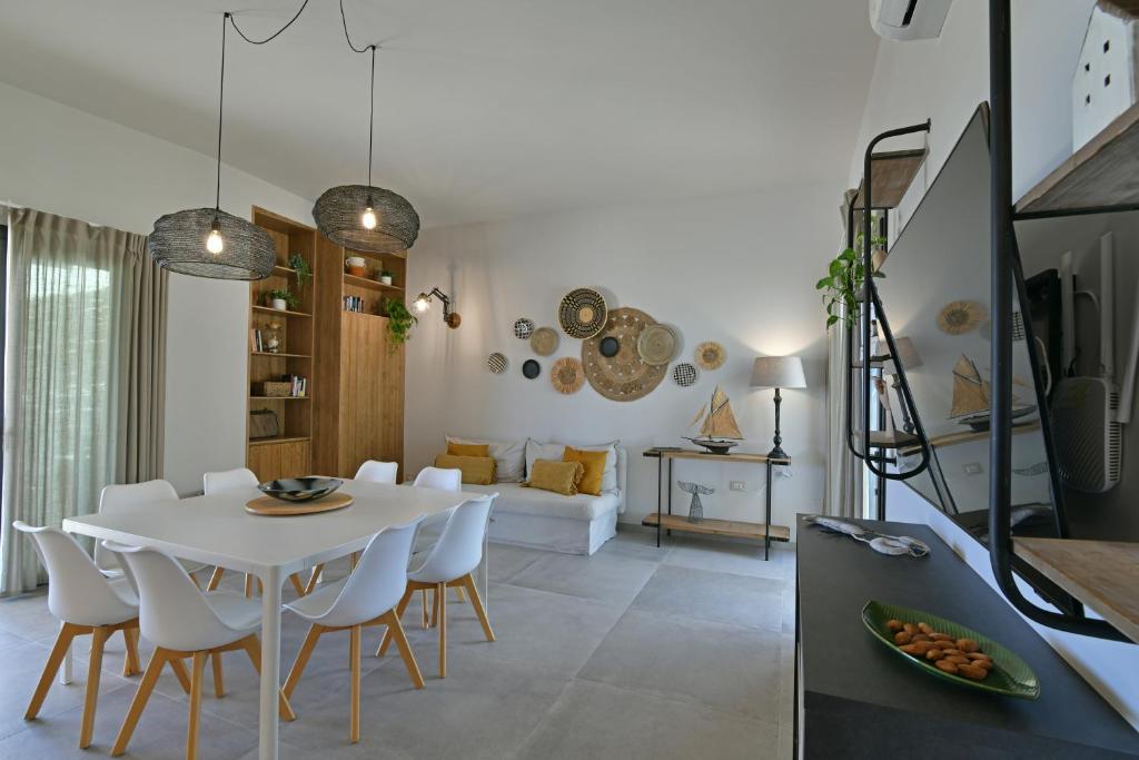 une salle à manger et un salon avec une table et des chaises blanches dans l'établissement VILLA RARIKI, à Scicli