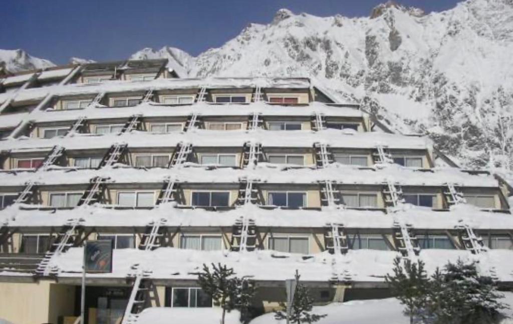 un bâtiment recouvert de neige avec une montagne en arrière-plan dans l'établissement Appart 5 pers Piau Engaly L Izard La Géla pistes à 50M, à Aragnouet