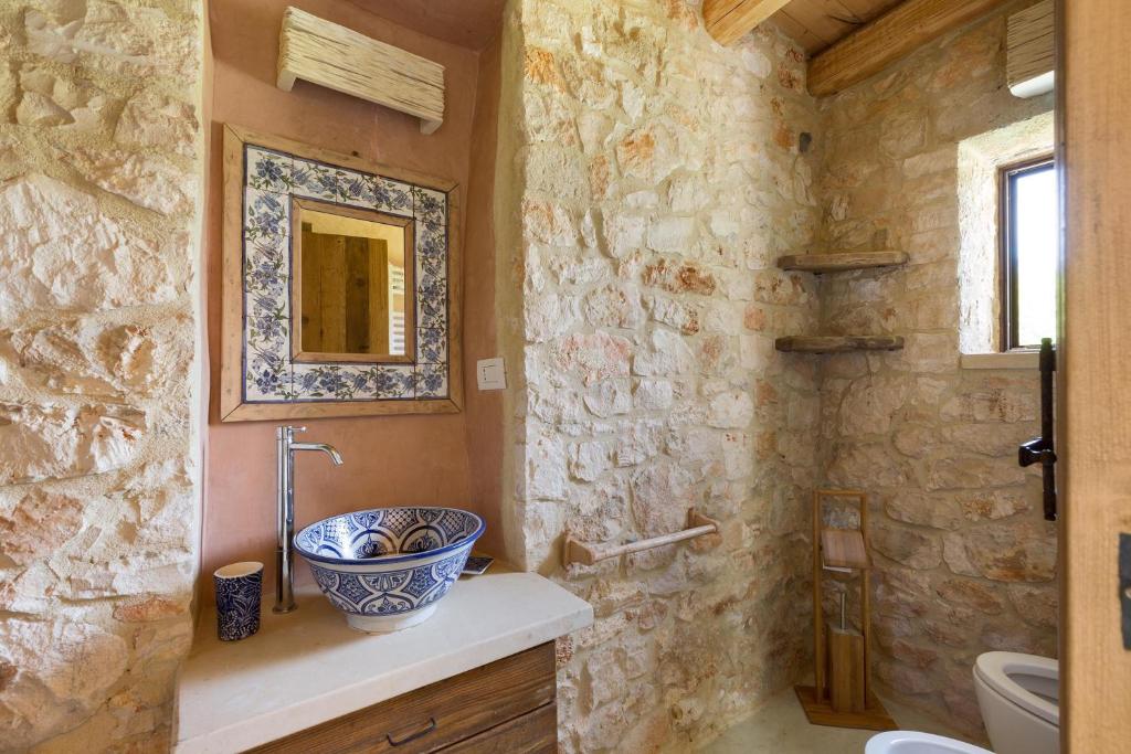 une salle de bain avec un lavabo et un mur en pierre dans l'établissement Villa Elaion by Perle di Puglia, à Marina di Pescoluse