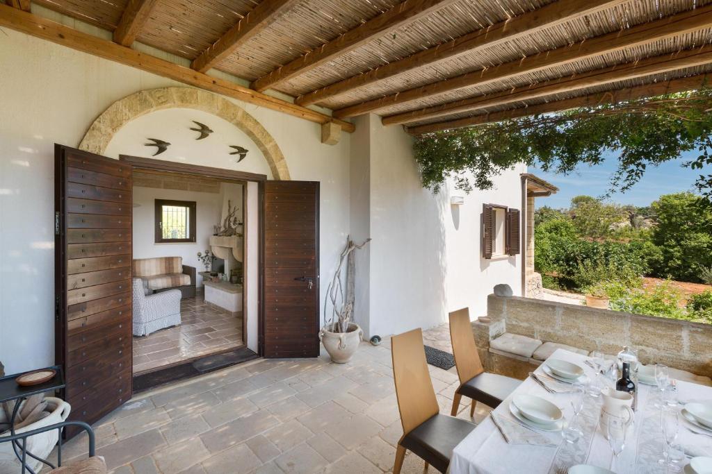 d'une terrasse avec une table, des chaises et une porte. dans l'établissement Villa Elaion by Perle di Puglia, à Marina di Pescoluse