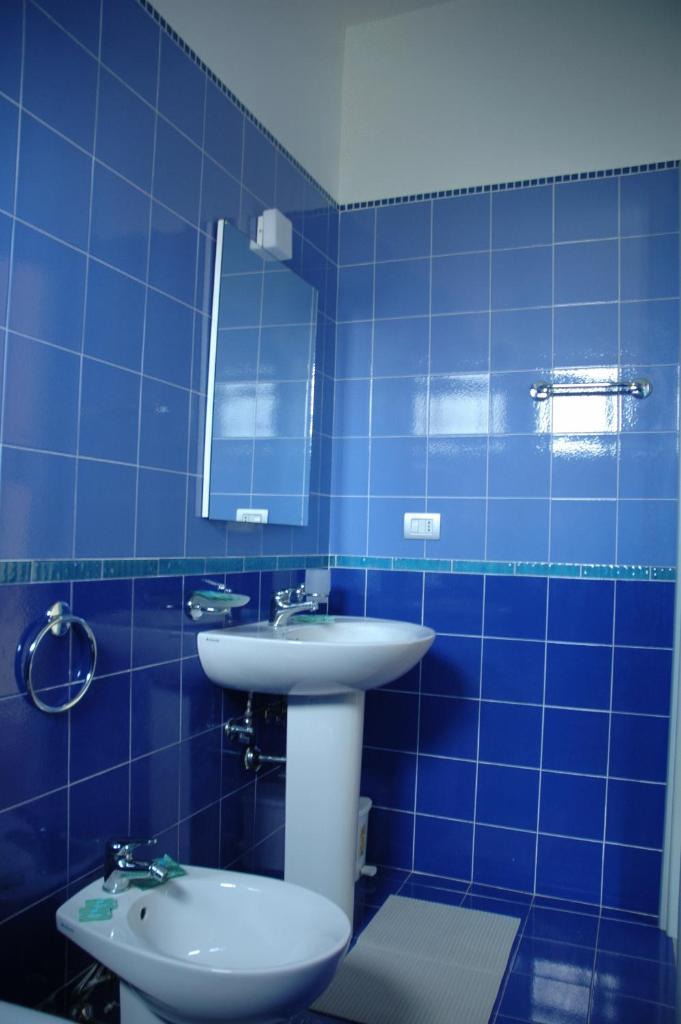 La salle de bains est pourvue de carrelage bleu, d'un lavabo et de toilettes. dans l'établissement Villa Comics, à Villammare 36 autres photos