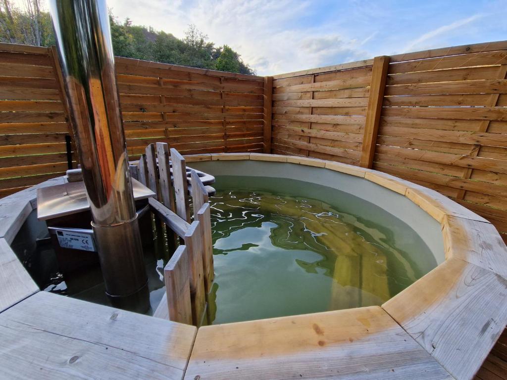une grande piscine d'eau dans une clôture en bois dans l'établissement La Bulle du Cheix, à Saint-Diéry