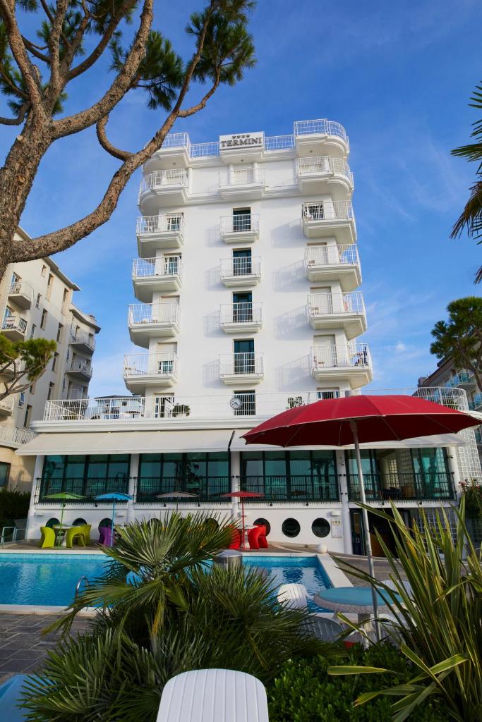 un grand bâtiment blanc avec une piscine devant dans l'établissement Termini Beach Hotel & Suites, à Lido di Jesolo