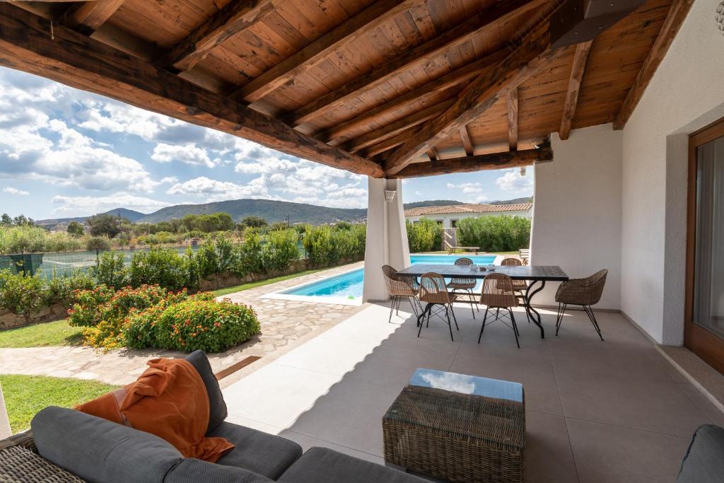un patio avec une table et des chaises et une piscine dans l'établissement Capannizza Villas, à Budoni