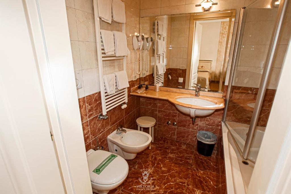 La salle de bains est pourvue de 2 toilettes, d'un lavabo et d'une douche. dans l'établissement Viktoria Palace Hotel, sur le Lido de Venise