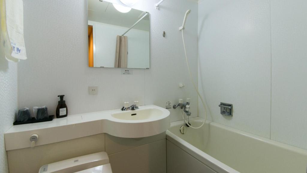 une salle de bain blanche avec un lavabo et une baignoire dans l'établissement Onsen Urashima, à Onomichi