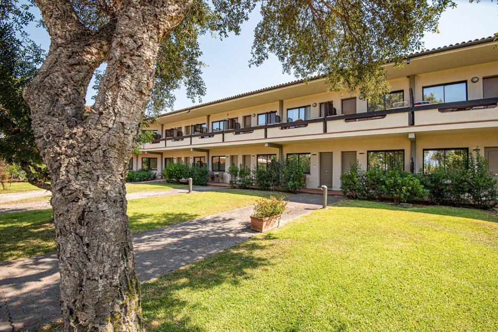 un immeuble d'appartements avec un arbre au premier plan dans l'établissement Hotel Airone isola d'Elba, à Portoferraio
