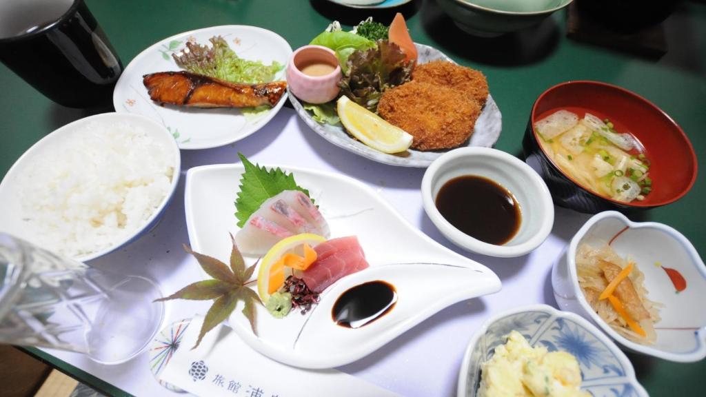 une table recouverte de assiettes de nourriture et de sauce dipping dans l'établissement Onsen Urashima, à Onomichi