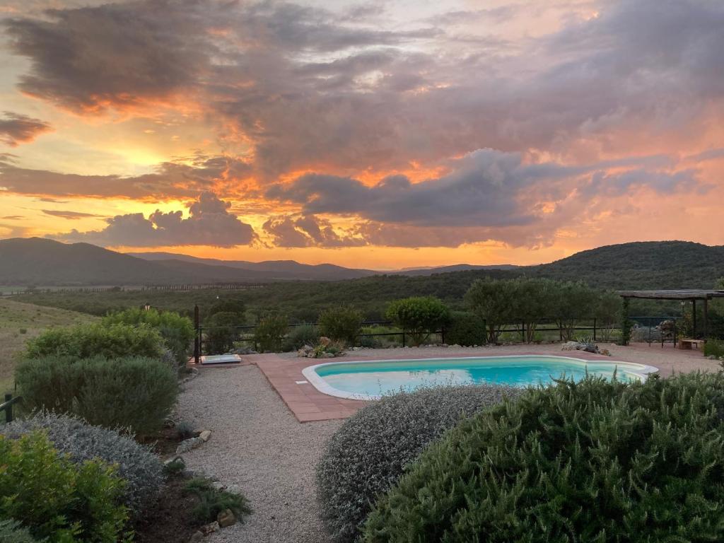 une piscine avec un coucher de soleil en arrière-plan dans l'établissement La Villa de I Casali del Troscio, à Capalbio