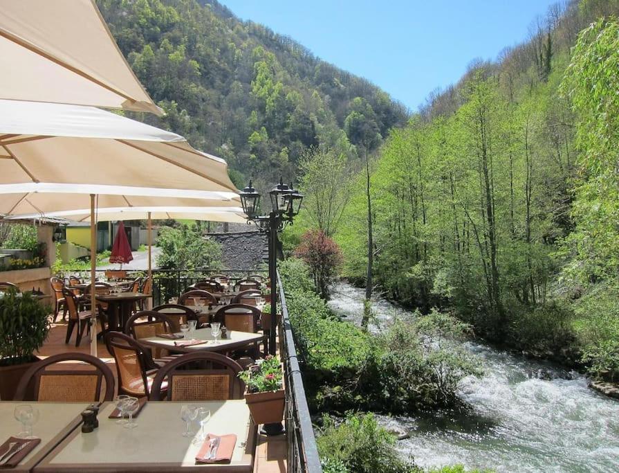un restaurant avec des tables et des chaises au bord d'une rivière dans l'établissement Le Loft Doré, à Ustou