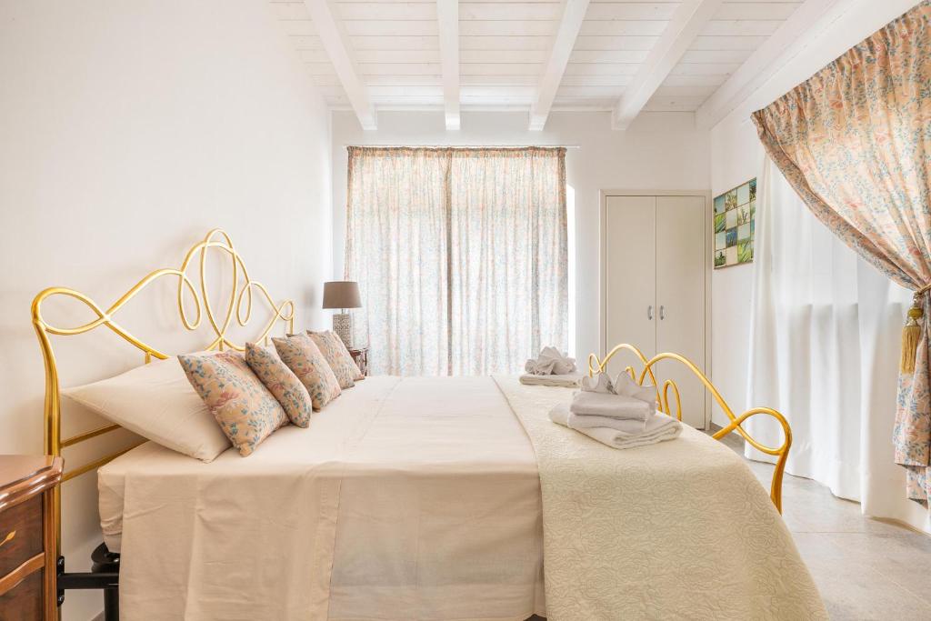 - une chambre dotée d'un grand lit avec des draps blancs et une fenêtre dans l'établissement Villa Theros by Perle di Puglia, à San Michele Salentino