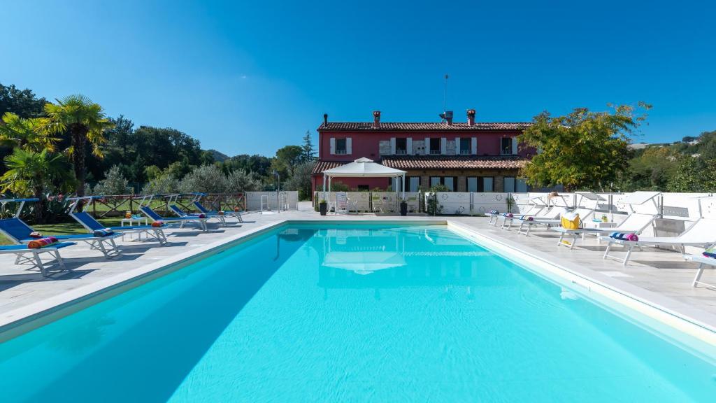 une piscine avec des chaises et une maison en arrière-plan dans l'établissement CASCINA MARIANNA 12&4, Emma Villas, à Fossombrone