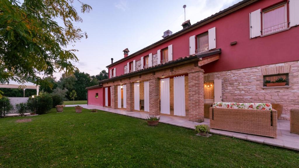 un grand bâtiment rose avec une pelouse devant lui dans l'établissement CASCINA MARIANNA 12&4, Emma Villas, à Fossombrone