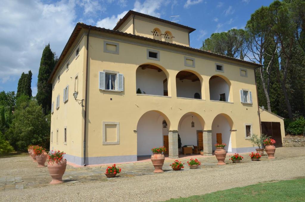 un grand bâtiment avec des pots de fleurs devant lui dans l'établissement Favolosa Villa in Toscana, à Lucignano