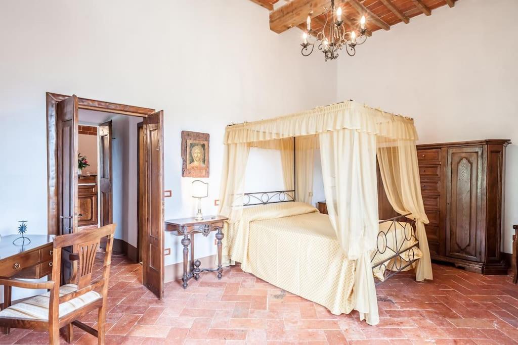 une chambre avec un lit à baldaquin et un bureau dans l'établissement Favolosa Villa in Toscana, à Lucignano